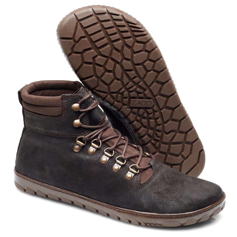 Ein Paar EXPEQ Obscure Waterproof Wanderstiefel von ZAQQ, mit High-Top-Design in Braun mit Wildleder-Finish und robusten Gummisohlen. Diese wasserdichten Stiefel haben Metallösen und einen gepolsterten Schaft für zusätzlichen Komfort. Die Outdoorsohle ist mit einem strukturierten Muster für optimalen Halt versehen, wobei ein Stiefel aufrecht steht und der andere angewinkelt, um das Design hervorzuheben.