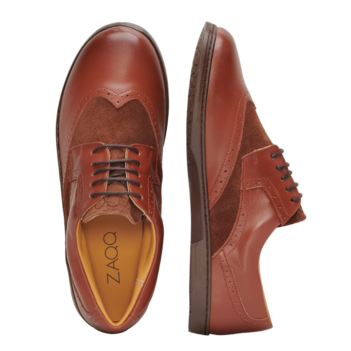 Ein Paar BRIQ Brogue Antique Cognac-Schuhe aus braunem Kalbsleder mit Schnürverschluss und Wildlederakzenten, perfekt als Businessschuhe. Ein Schuh ist von oben zu sehen, der andere von der Seite, beide heben ein elegantes Design hervor. Die senfgelbe Innensohle zeigt stolz den Markennamen ZAQQ.