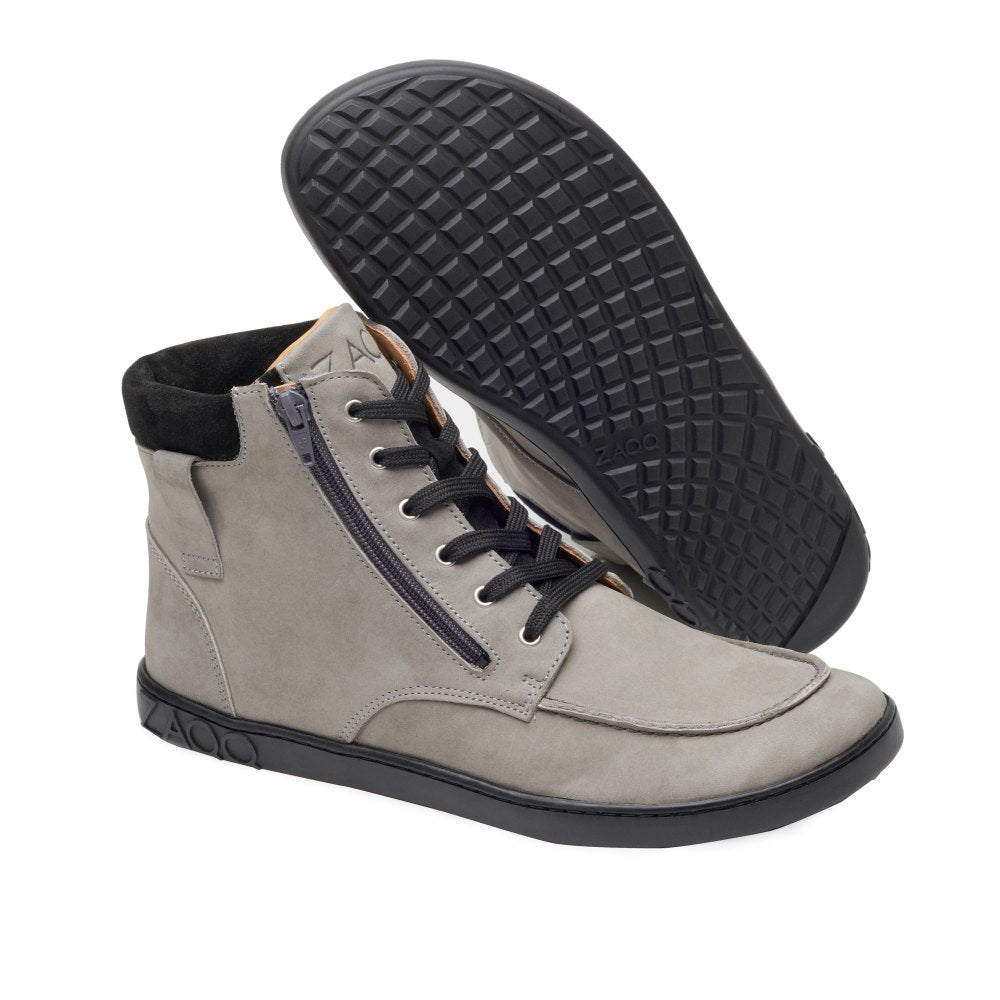 Die ROQA Grey High-Top-Sneaker von ZAQQ kombinieren flexiblen Komfort mit Stil. Diese grauen Schuhe mit schwarzer Sohle haben seitliche Reißverschlüsse und Schnürung vorne. Sie sind so konzipiert, dass ein Schuh flach liegt, während der andere hochgestellt ist, um das Gittermuster der Sohle zur Geltung zu bringen.