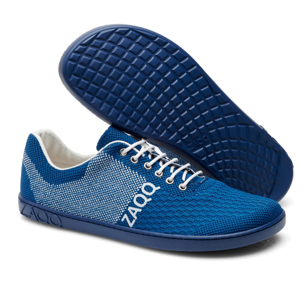 Der QNIT Mare von ZAQQ ist ein Paar blauer Sport-Sneaker mit weißen Schnürsenkeln und einer strukturierten ZAQQ-Sohle. Dieser vegane Barfußschuh verfügt über ein Strickdesign mit „ZAQQ“ in Weiß auf der Seite und ist aus atmungsaktivem Baumwollstrickgewebe für optimalen Komfort und Luftzirkulation gefertigt.